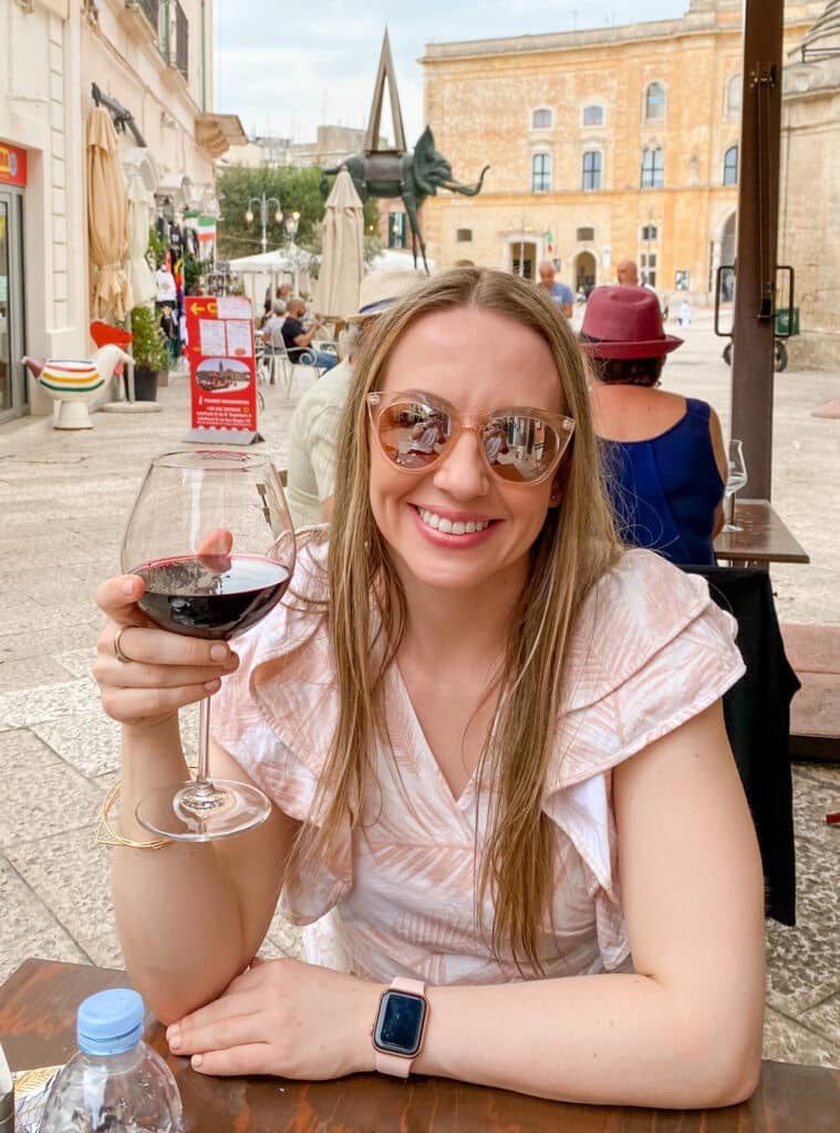 jillian, travel and wellness influencer, drinking a glass of red wine