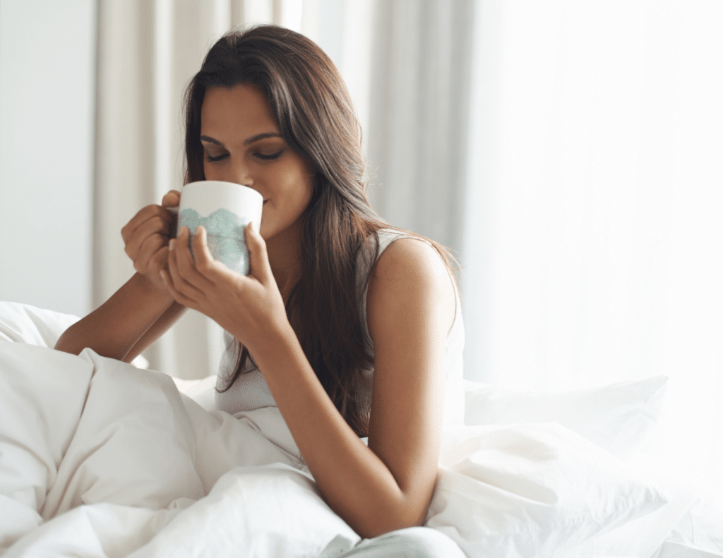 woman drinking early morning coffee in bed