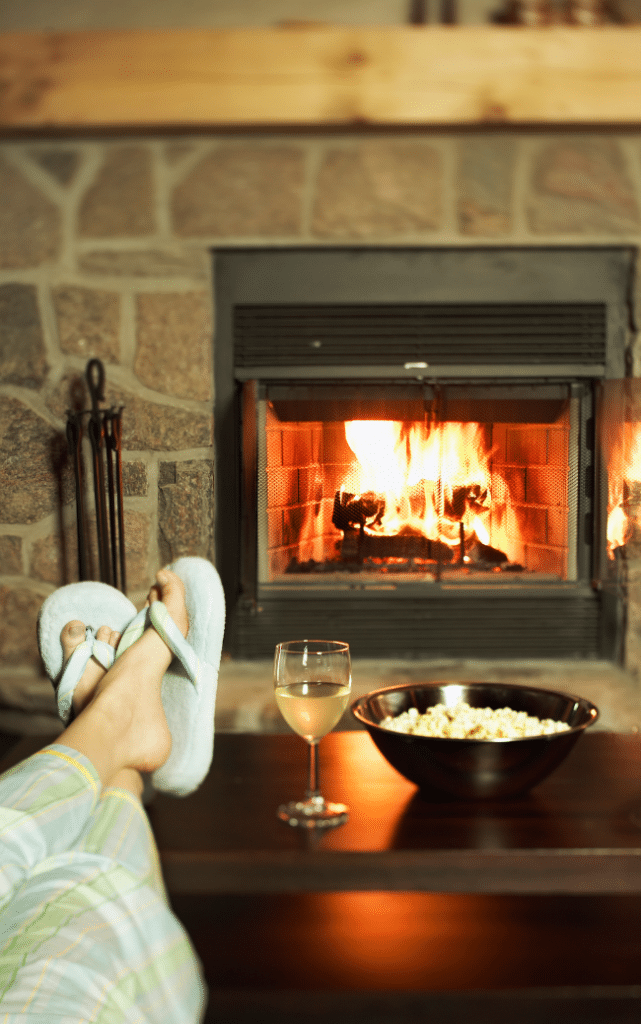woman sitting by the fire place with glass of wine and popcorn
